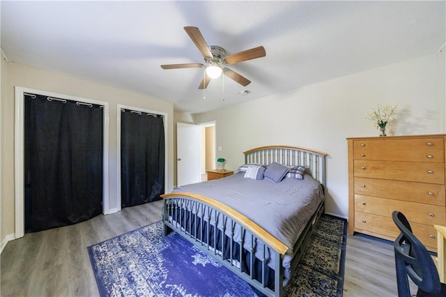 bedroom featuring multiple closets, ceiling fan, and hardwood / wood-style floors