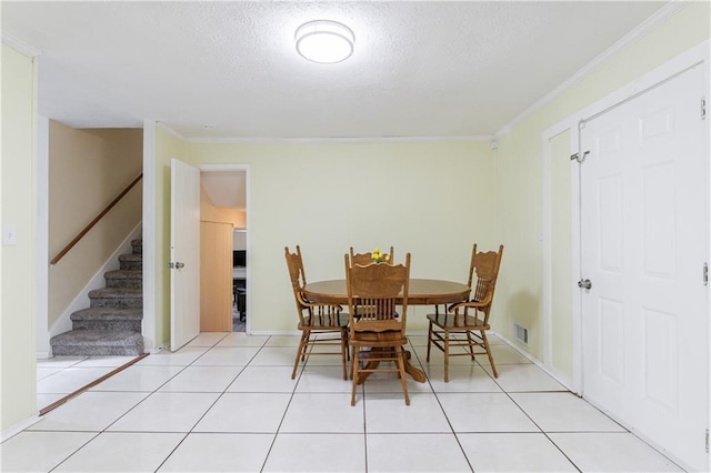 tiled dining space with ornamental molding and a textured ceiling