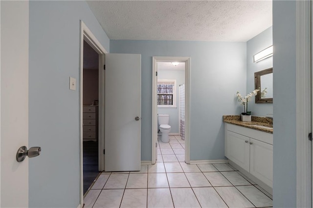 bathroom with vanity, tile patterned flooring, a textured ceiling, and toilet