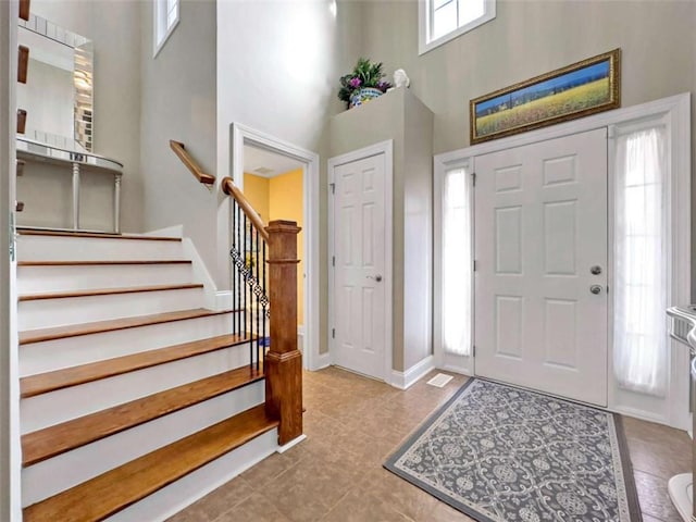 entrance foyer featuring a towering ceiling, stairs, and baseboards