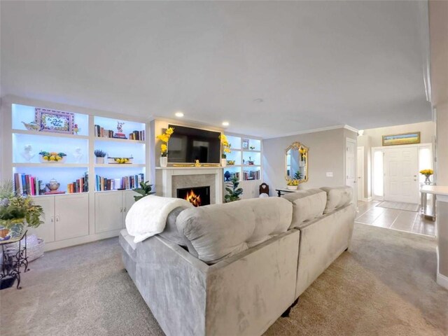 living area featuring carpet floors, recessed lighting, a warm lit fireplace, and ornamental molding