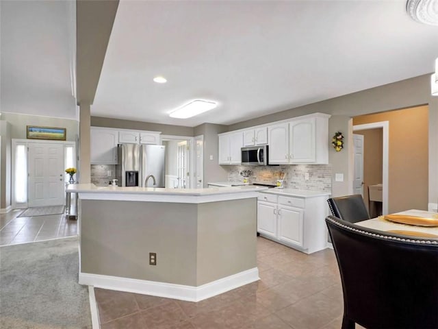 kitchen with tasteful backsplash, appliances with stainless steel finishes, white cabinets, and light countertops