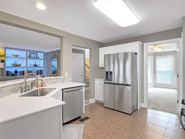 kitchen featuring visible vents, appliances with stainless steel finishes, a sink, white cabinetry, and backsplash