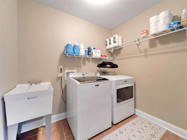 laundry area featuring light tile patterned floors, laundry area, a sink, baseboards, and washer and dryer