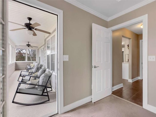 interior space with carpet floors, ornamental molding, a ceiling fan, and baseboards