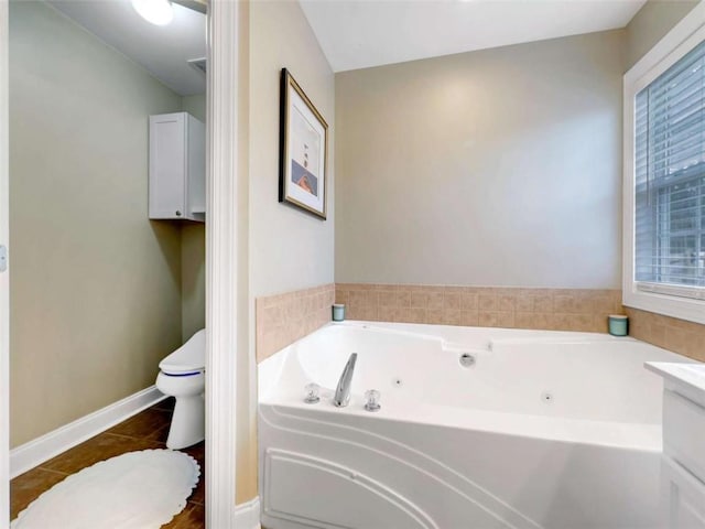 full bath featuring toilet, tile patterned flooring, a tub with jets, and baseboards