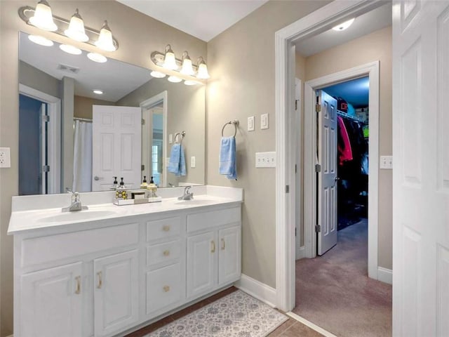 full bathroom featuring visible vents, a sink, baseboards, and double vanity