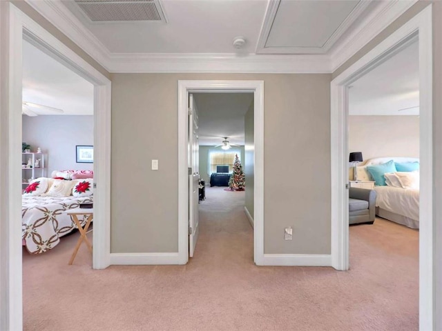 hall featuring light carpet, attic access, visible vents, baseboards, and crown molding