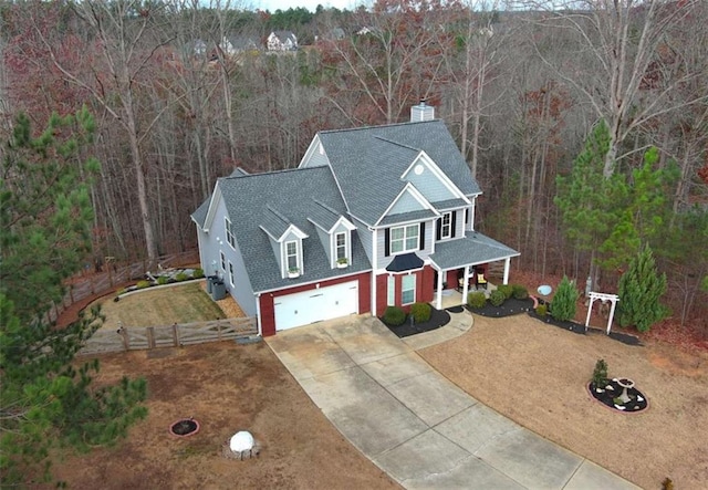 view of front of property featuring roof with shingles, covered porch, an attached garage, fence, and driveway