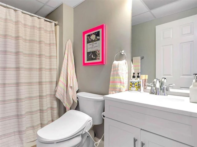 full bathroom with toilet, a shower with curtain, a drop ceiling, and vanity