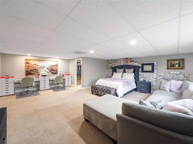 carpeted bedroom with a paneled ceiling, a spacious closet, baseboards, and recessed lighting