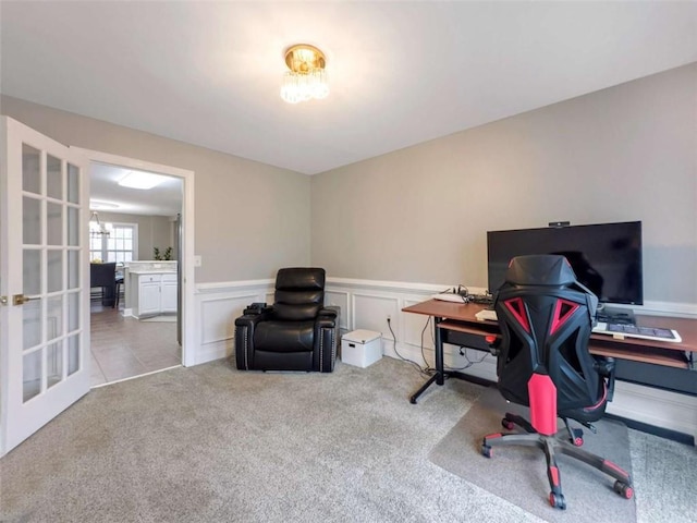 office featuring a chandelier, a decorative wall, carpet floors, french doors, and wainscoting