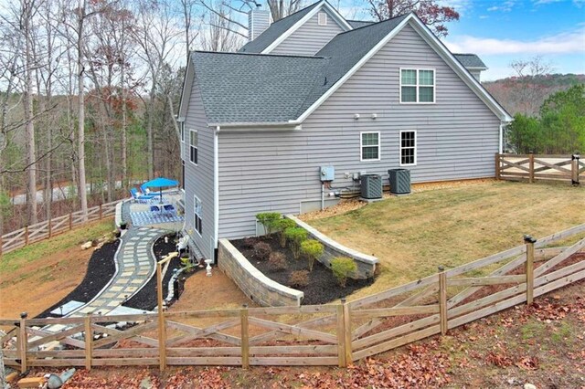 back of house with a deck, a fenced backyard, a yard, roof with shingles, and a chimney