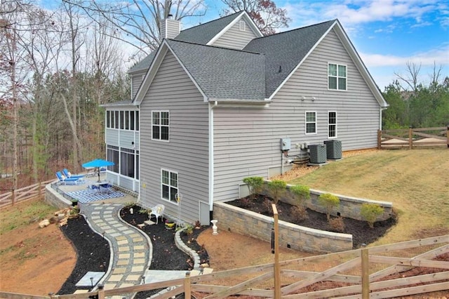 back of property featuring central AC unit, a vegetable garden, a sunroom, a chimney, and fence