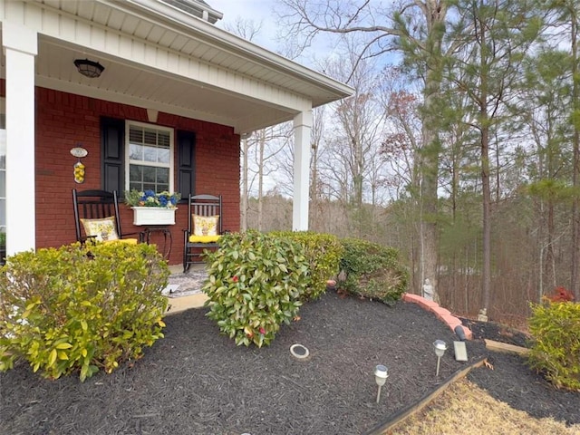 exterior space with a porch and brick siding