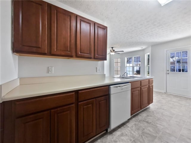 kitchen with a ceiling fan, dishwasher, a peninsula, light countertops, and a textured ceiling