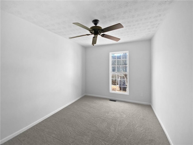 carpeted empty room featuring visible vents, ceiling fan, a textured ceiling, and baseboards