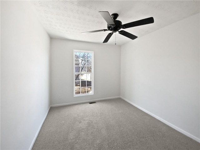 spare room featuring carpet, visible vents, baseboards, and a textured ceiling
