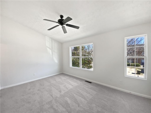 carpeted empty room with a ceiling fan, visible vents, and baseboards