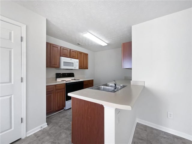 kitchen featuring white microwave, a peninsula, a sink, light countertops, and electric range oven