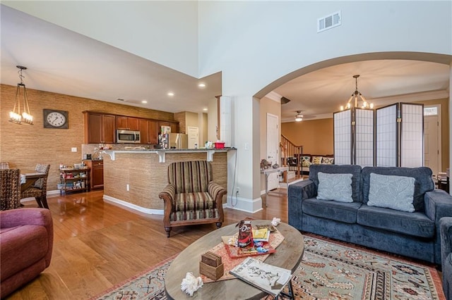 13943 Sunfish Bnd, Alpharetta, GA 30004 - living room featuring arched walkways, an inviting chandelier, wood finished floors, and visible vents