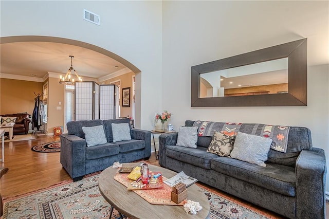 13943 Sunfish Bnd, Alpharetta, GA 30004 - living room with visible vents, crown molding, arched walkways, wood finished floors, and a notable chandelier