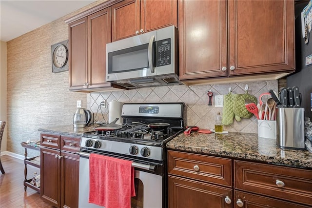 13943 Sunfish Bnd, Alpharetta, GA 30004 - kitchen with backsplash, wood finished floors, baseboards, dark stone countertops, and stainless steel appliances