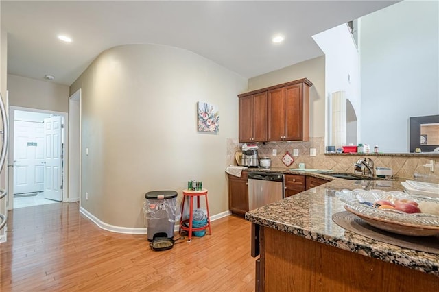 13943 Sunfish Bnd, Alpharetta, GA 30004 - kitchen featuring brown cabinetry, light wood-type flooring, a sink, dark stone countertops, and dishwasher