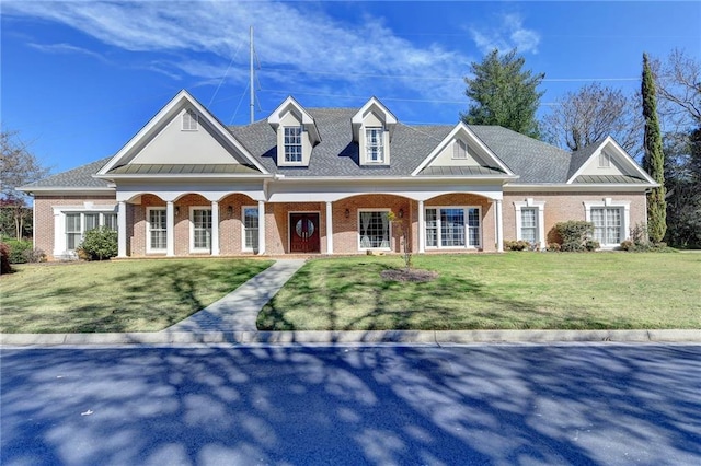 view of front facade featuring a standing seam roof, brick siding, metal roof, and a front lawn