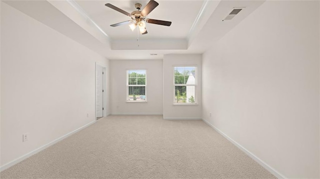 unfurnished room with ceiling fan, light carpet, visible vents, baseboards, and a tray ceiling