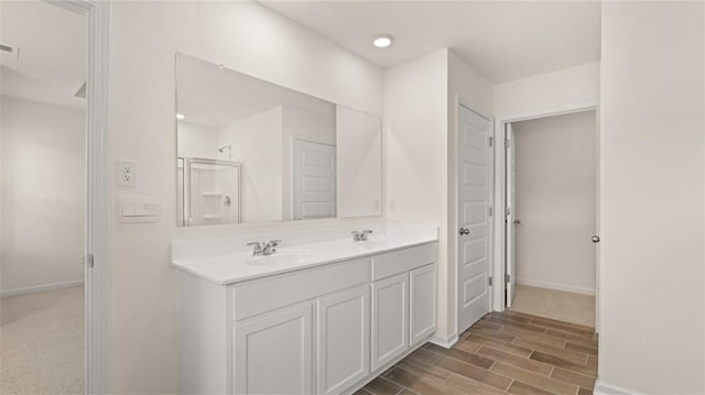 bathroom featuring baseboards, double vanity, a sink, and wood tiled floor