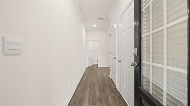 hall featuring dark wood-style floors, crown molding, recessed lighting, visible vents, and baseboards