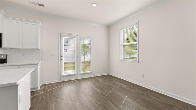 unfurnished dining area with ornamental molding, dark wood-type flooring, visible vents, and baseboards