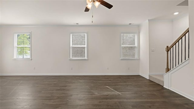 unfurnished room featuring ceiling fan, baseboards, stairs, dark wood finished floors, and crown molding