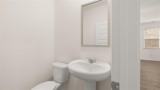 bathroom featuring baseboards, a sink, toilet, and wood finished floors