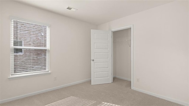 unfurnished bedroom featuring carpet floors, baseboards, multiple windows, and visible vents