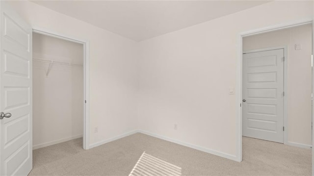 unfurnished bedroom with light carpet, a closet, and baseboards