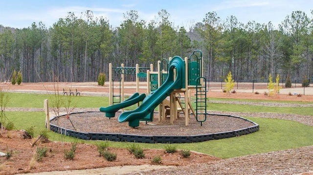 community jungle gym featuring a lawn and a wooded view