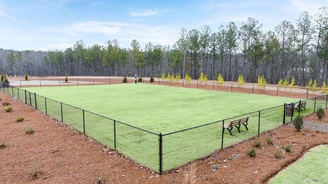 view of sport court featuring a yard, a rural view, fence, and a forest view