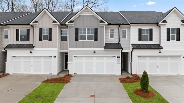 townhome / multi-family property featuring driveway, a standing seam roof, board and batten siding, and brick siding