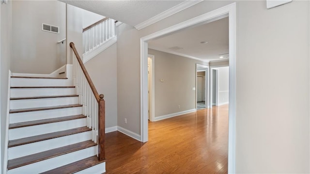 staircase featuring hardwood / wood-style flooring and ornamental molding