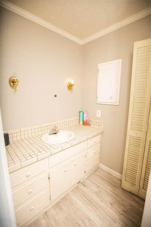 bathroom featuring crown molding, wood-type flooring, and vanity