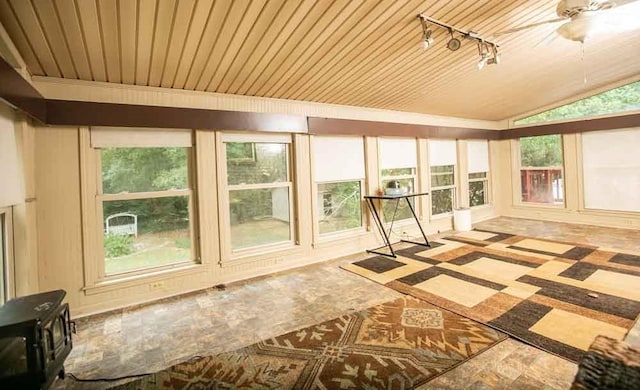 unfurnished sunroom featuring ceiling fan, wood ceiling, track lighting, and a wealth of natural light