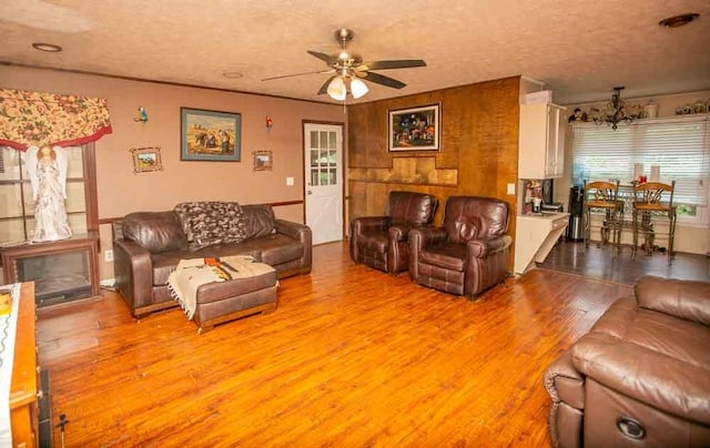 living room featuring a textured ceiling, ceiling fan with notable chandelier, and light hardwood / wood-style floors