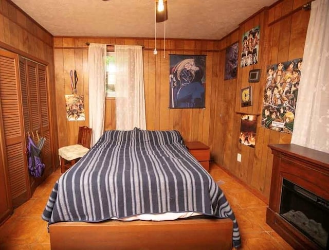 bedroom with wooden walls, a closet, a fireplace, and a textured ceiling