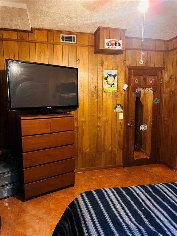 bedroom featuring a textured ceiling and wood walls