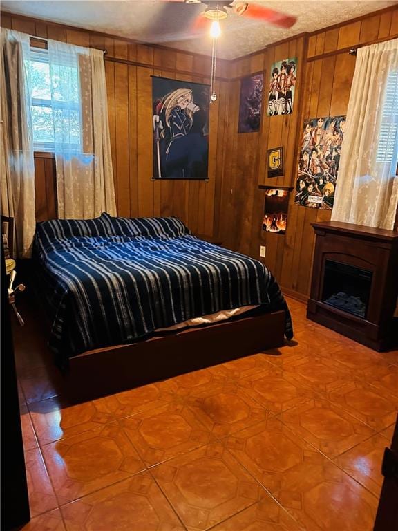 bedroom with a fireplace, wood walls, and ceiling fan