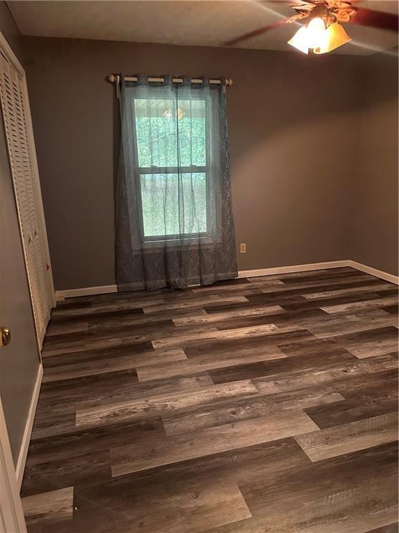 empty room with ceiling fan and dark wood-type flooring