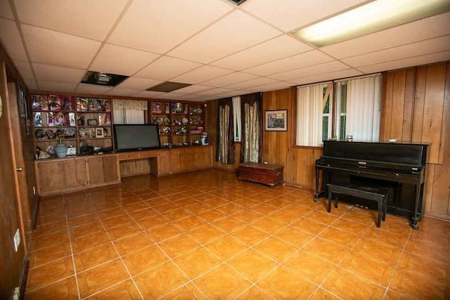 bar with light tile patterned floors, a paneled ceiling, and wood walls