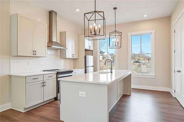 kitchen featuring appliances with stainless steel finishes, dark hardwood / wood-style floors, white cabinetry, a kitchen island with sink, and wall chimney exhaust hood